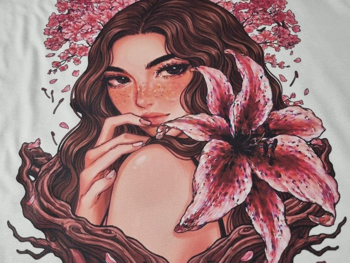 Ilustração a cores estampada em DTF sobre t-shirt clara: retrato feminino com flores, da coleção Muse of Chaos, com o detalhe do tecido visível