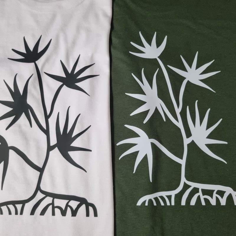 T-shirts branca e verde-militar com a mesma ilustração She Jaguar, em duas cores de estampagem